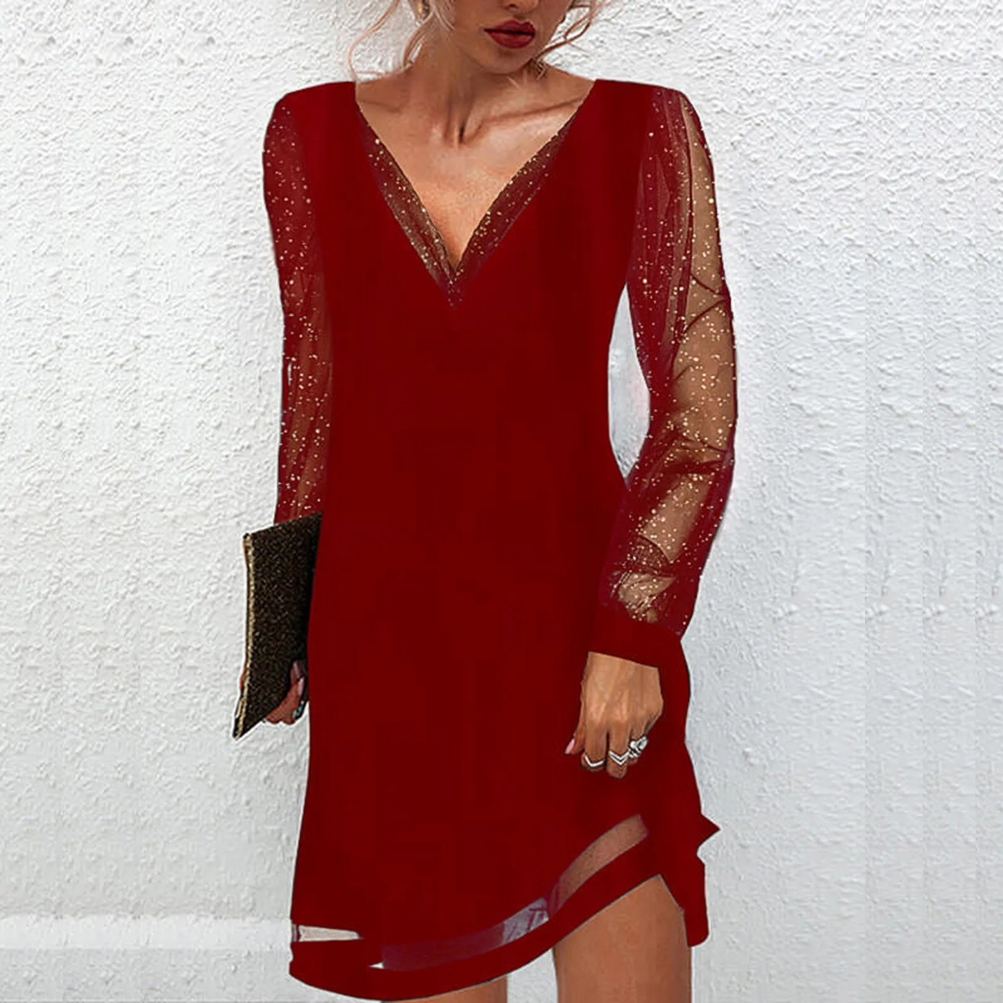 Abito rosso elegante con maniche trasparenti e dettagli brillanti, scollatura a V, indossato da donna con pochette nera. Moda femminile chic.