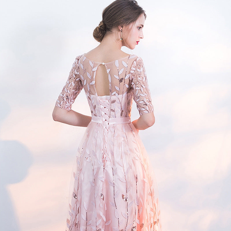 Donna in abito da sera rosa con dettagli floreali e trasparenze, vista posteriore. Moda elegante, abbigliamento femminile, tendenze 2023.