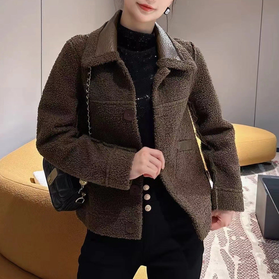 Donna con giacca in lana marrone, maglia nera e pantaloni neri, seduta su divano giallo. Moda autunnale, stile casual chic.