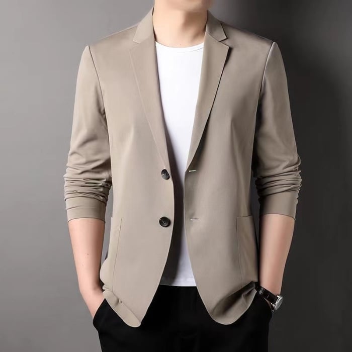 Giacca elegante beige da uomo su sfondo grigio, abbinata a t-shirt bianca e pantaloni neri. Moda maschile, abbigliamento formale casual.