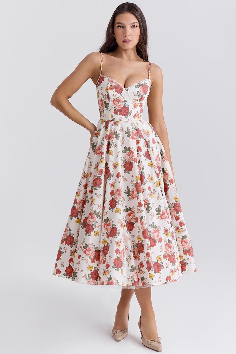 Donna in abito floreale estivo bianco e rosso, scollo a cuore, spalline sottili, lunghezza midi. Moda femminile elegante, abbigliamento estivo.
