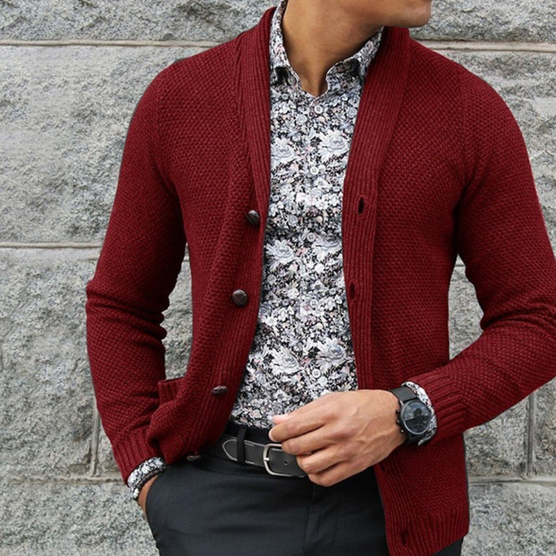 Uomo con cardigan rosso, camicia a fiori bianca e nera, orologio nero, pantaloni scuri. Moda maschile elegante, stile autunnale casual.