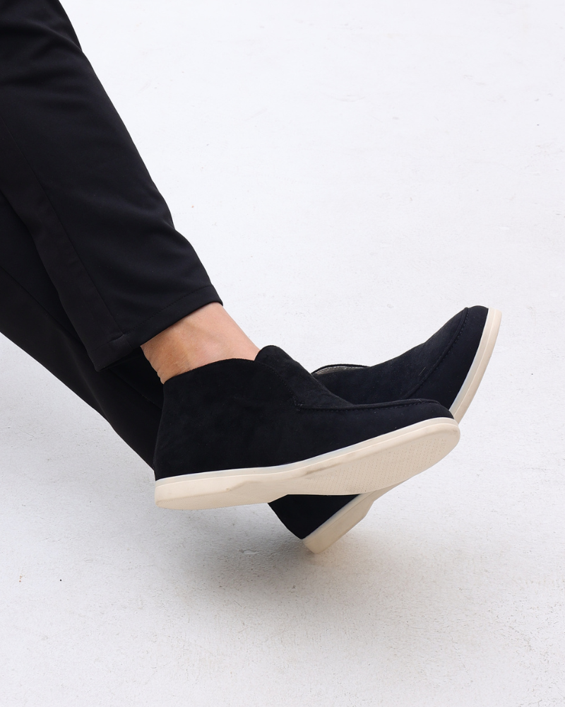 Scarpe uomo nere in pelle scamosciata con suola bianca, indossate con pantaloni neri. Calzature eleganti e casual per moda maschile.