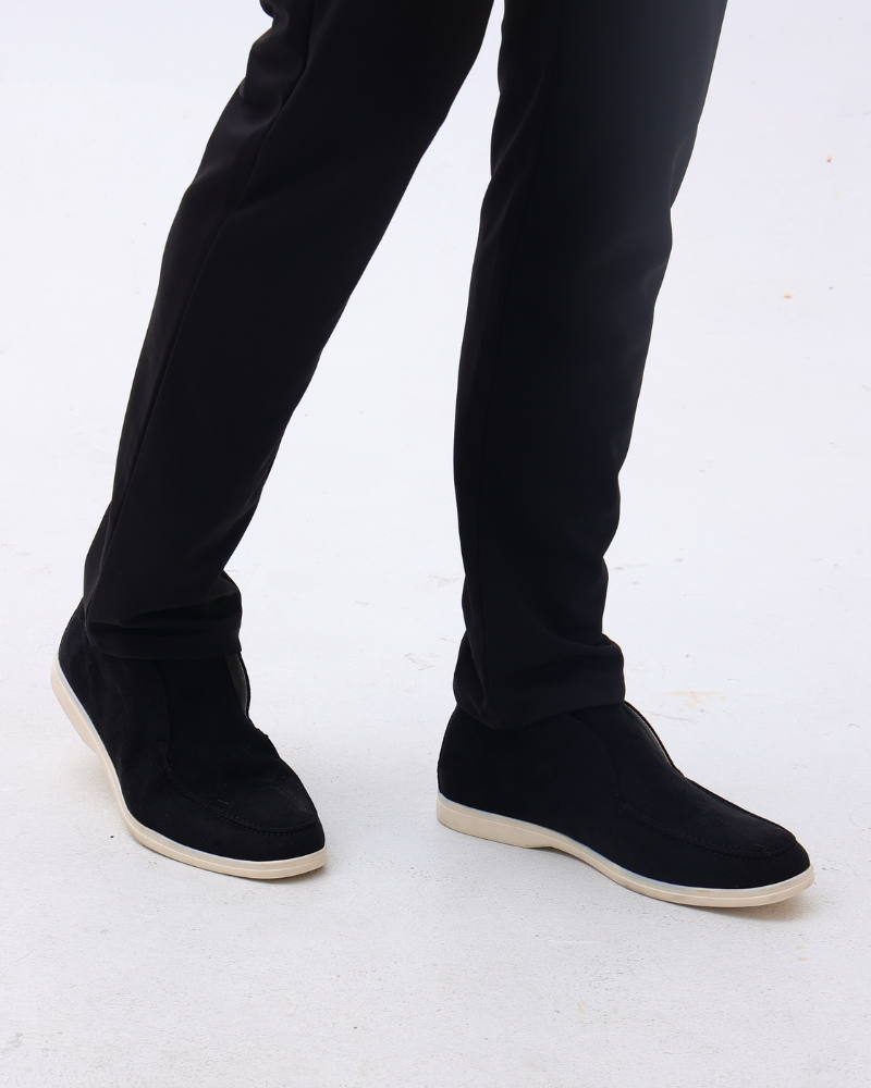 Pantaloni neri eleganti e scarpe nere in pelle scamosciata con suola bianca su sfondo bianco. Moda uomo, abbigliamento formale, calzature di tendenza.