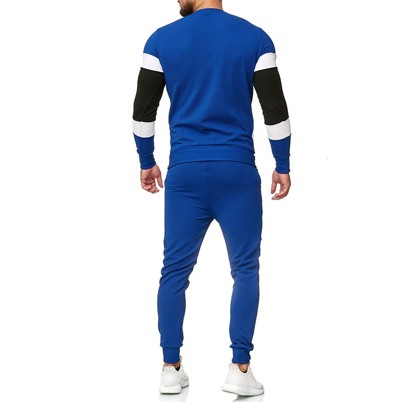 Uomo in tuta sportiva blu con dettagli neri e bianchi, visto di spalle. Indossa scarpe da ginnastica bianche. Moda casual maschile.