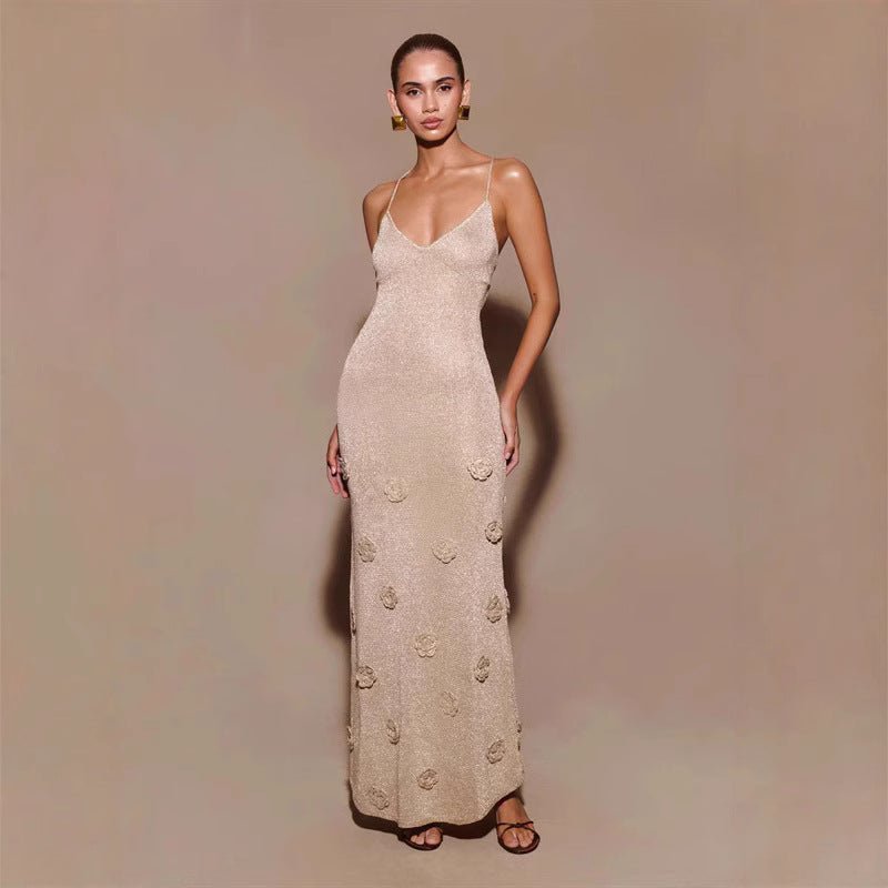 Abito lungo elegante color beige con spalline sottili e decorazioni floreali, indossato da una modella su sfondo neutro. Moda femminile sofisticata.