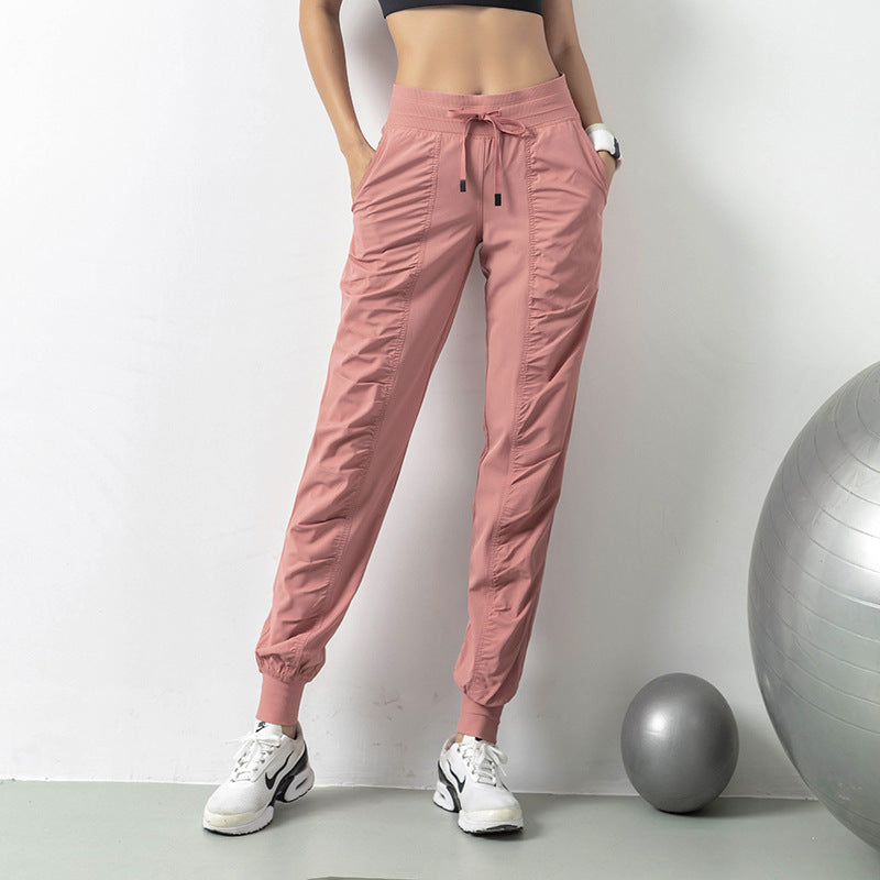 Pantaloni sportivi rosa da donna, con elastico in vita e polsini, abbinati a scarpe da ginnastica bianche. Fitness, moda, abbigliamento sportivo.