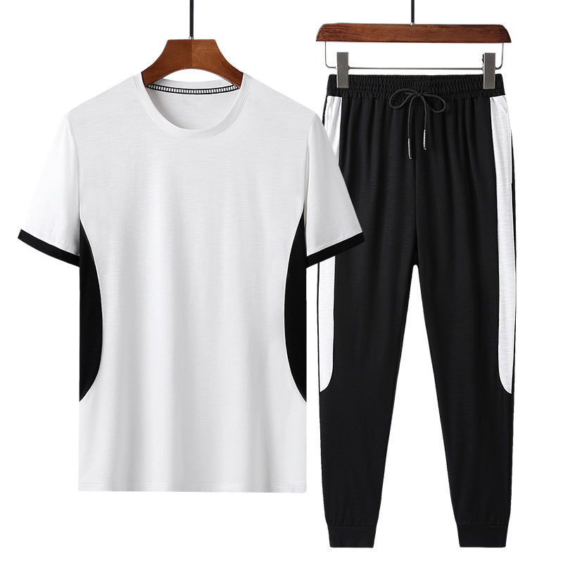 Completo sportivo uomo bianco e nero, t-shirt e pantaloni con dettagli a contrasto, ideale per allenamento e tempo libero.
