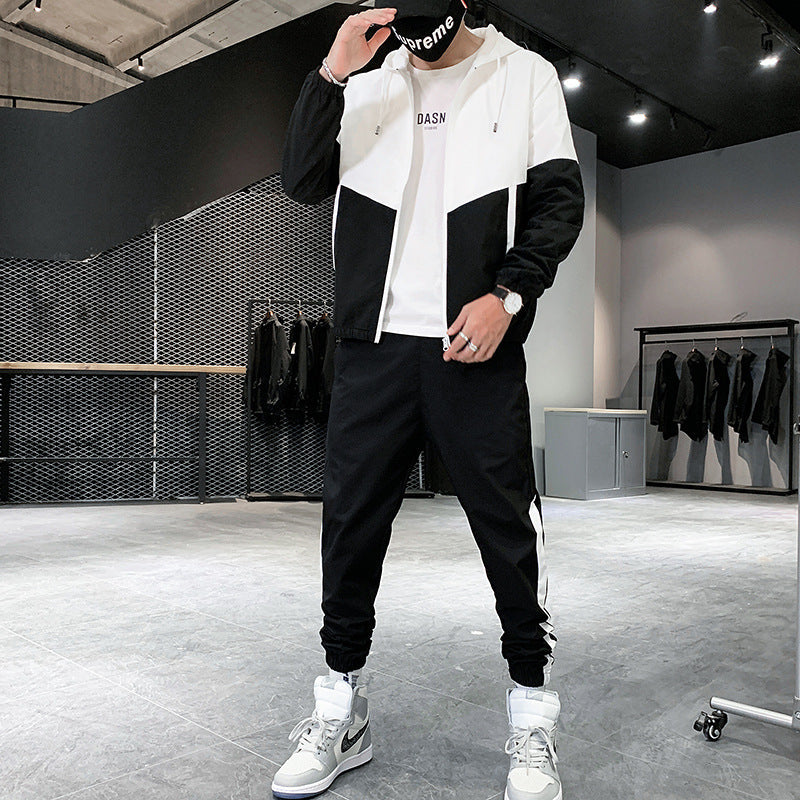 Uomo in tuta sportiva bianca e nera, cappuccio, scarpe da ginnastica grigie e bianche, in negozio di abbigliamento moderno. Moda streetwear casual.