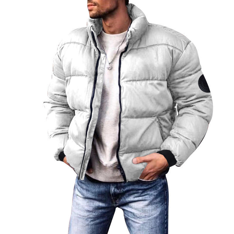 Giacca invernale uomo bianca imbottita, stile casual, con colletto alto e tasche, abbinata a jeans blu. Moda maschile autunno inverno.