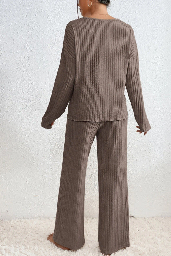 Donna in abbigliamento lounge marrone, maglia a coste, pantaloni larghi, sfondo bianco. Stile casual, moda autunnale, comfort domestico.