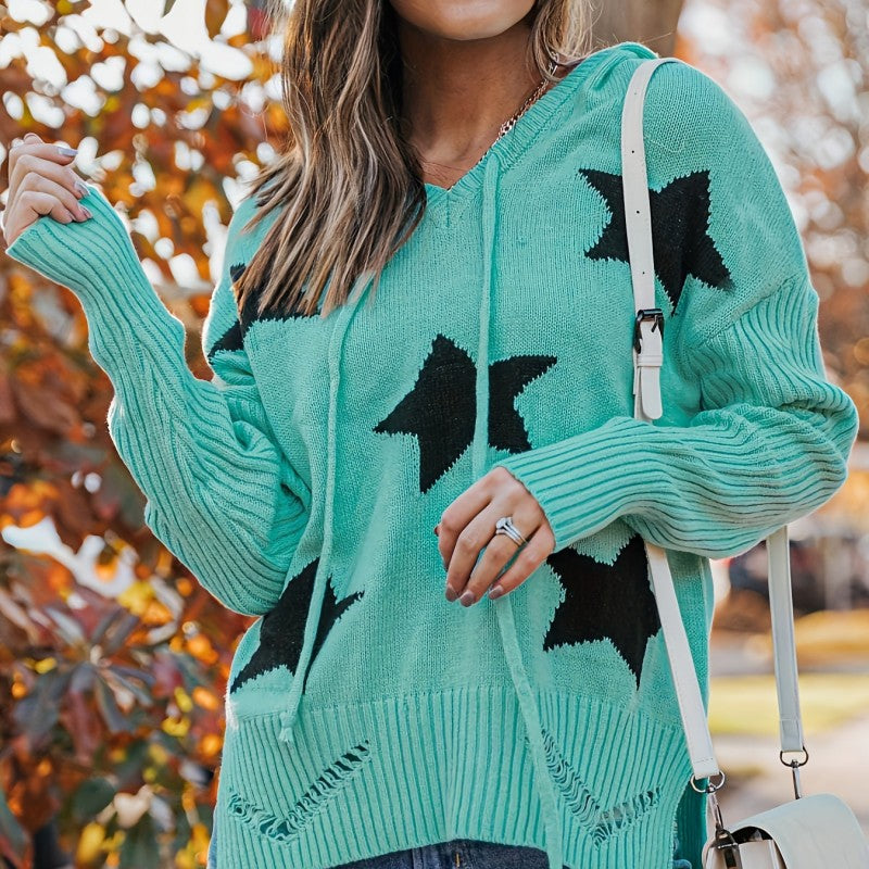 Donna con maglione verde acqua con stelle nere, borsa bianca a tracolla, sfondo autunnale. Moda autunno, abbigliamento casual, stile femminile.