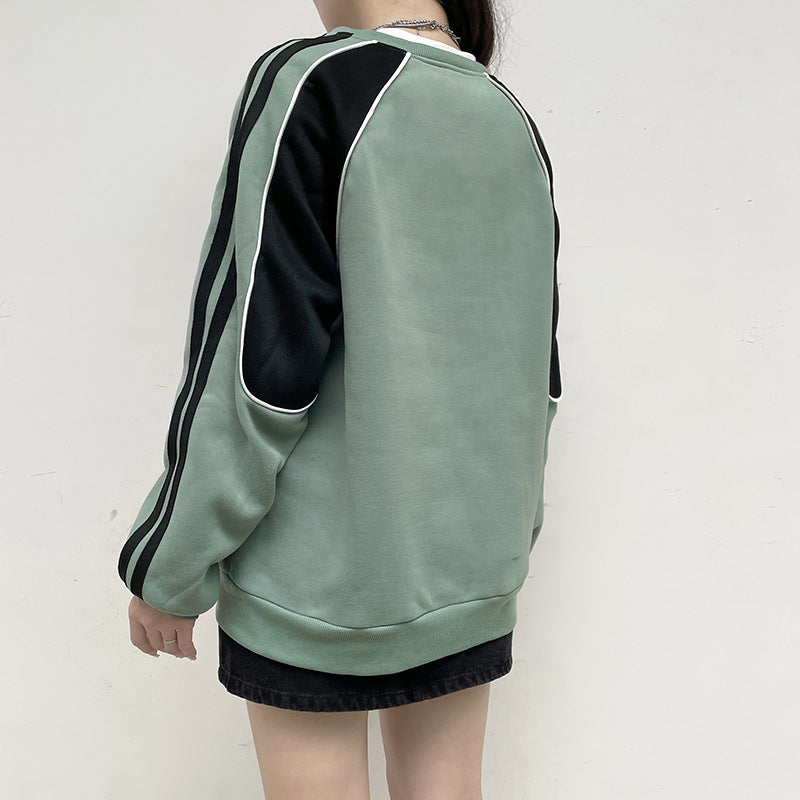 Donna con felpa verde e nera, design a righe, maniche lunghe, sfondo bianco. Moda casual, abbigliamento streetwear, tendenze autunno inverno.