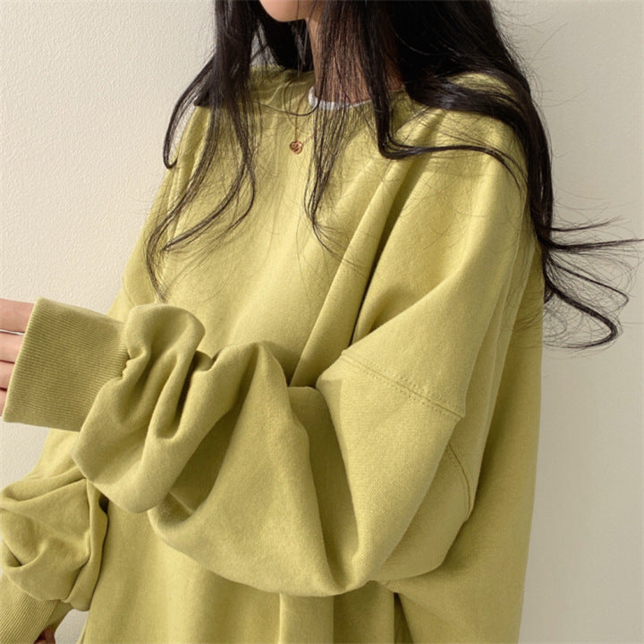 Donna con maglione oversize verde chiaro, capelli lunghi e collana dorata. Moda casual autunnale, abbigliamento comodo e trendy.