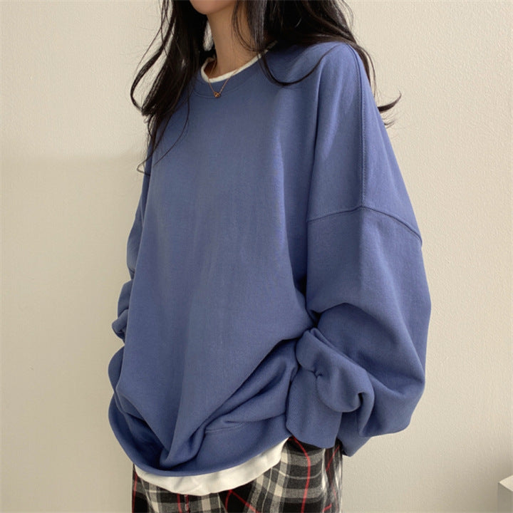 Donna con maglione oversize blu, camicia bianca e pantaloni a quadri. Moda casual autunnale, abbigliamento comodo e trendy.