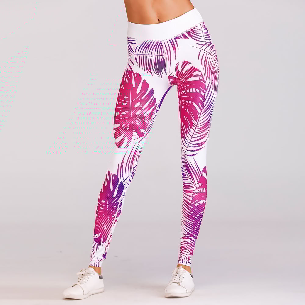 Leggings sportivi donna con stampa foglie tropicali rosa e viola, vita alta, abbinati a scarpe da ginnastica bianche su sfondo neutro.