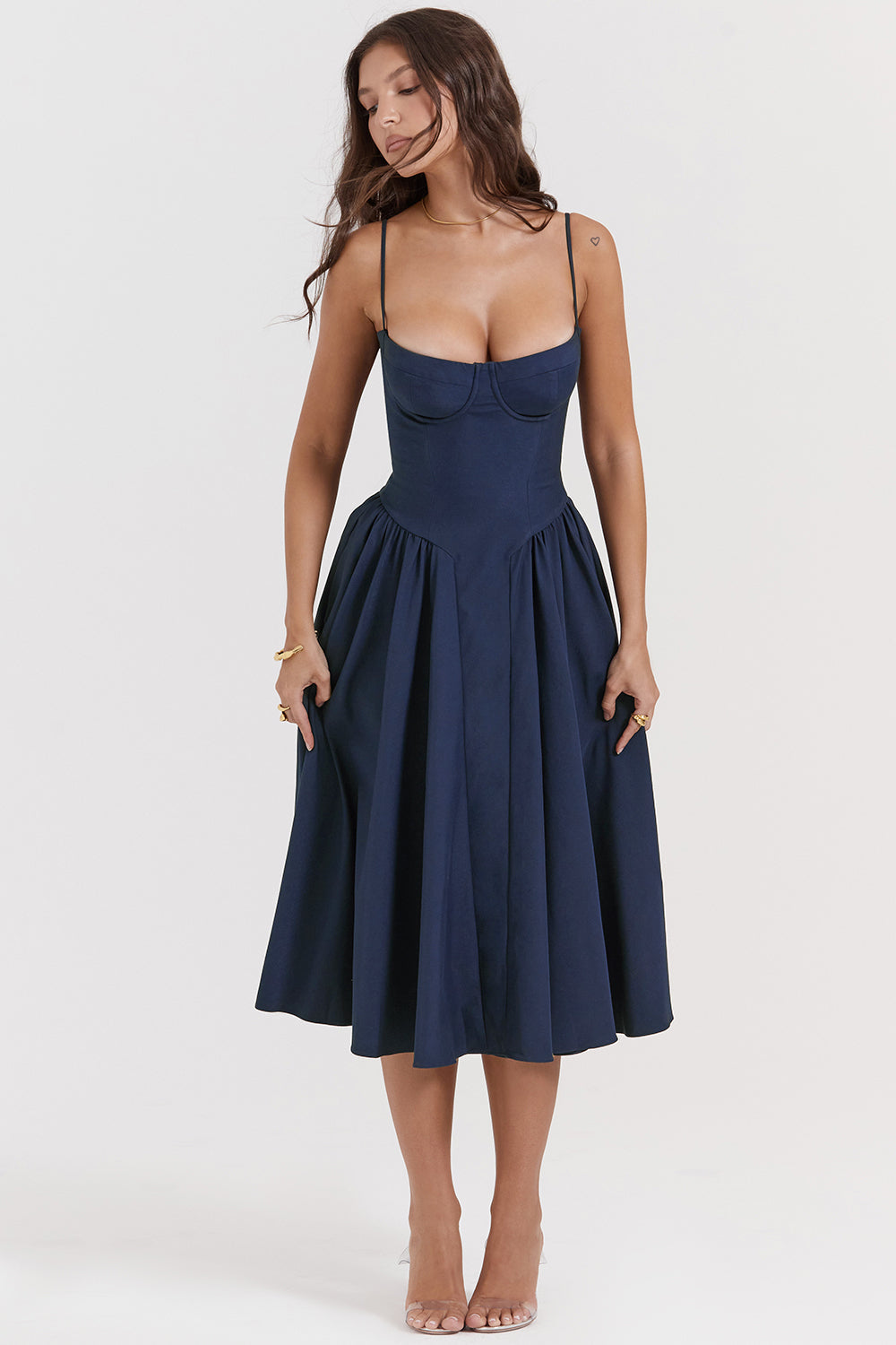 Donna con abito blu scuro elegante, spalline sottili, scollatura a cuore, gonna ampia. Moda femminile, abbigliamento da sera, stile sofisticato.