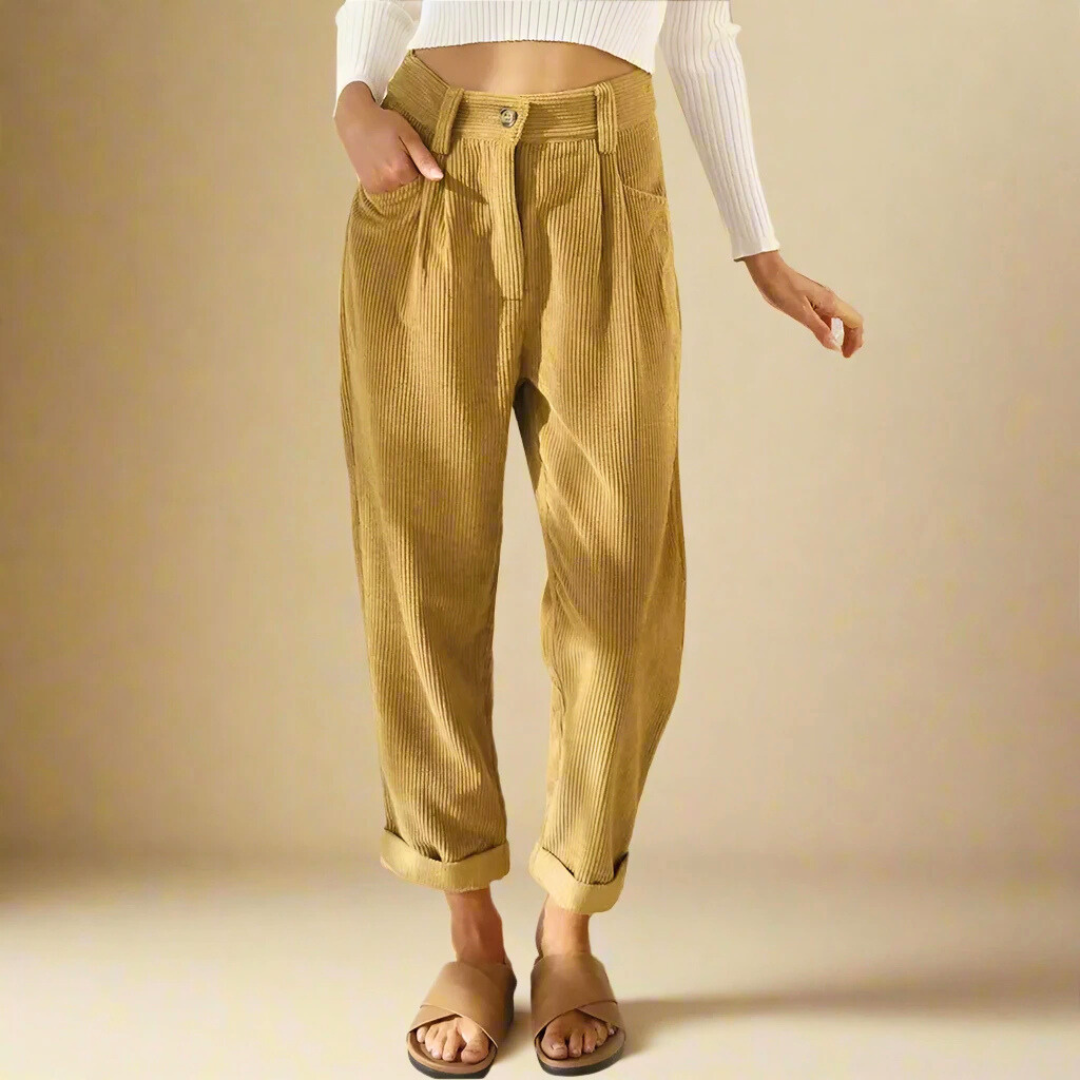 Pantaloni a coste beige da donna, vita alta, abbinati a maglia bianca a maniche lunghe. Stile casual, moda autunnale, calzature aperte.