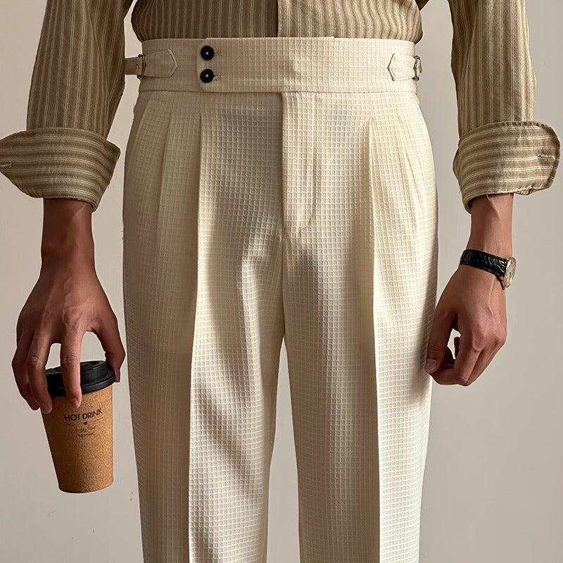 Uomo in camicia a righe e pantaloni eleganti bianchi, tiene un bicchiere di caffè. Moda maschile, abbigliamento formale, stile contemporaneo.