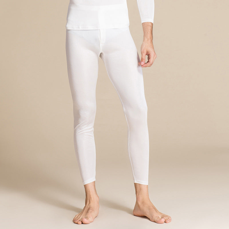 Uomo in intimo termico bianco, pantaloni lunghi aderenti, su sfondo beige. Abbigliamento intimo maschile, comfort e calore.