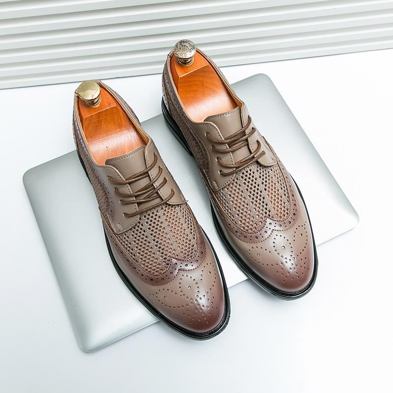 Scarpe eleganti uomo in pelle marrone, stile brogue, su laptop argento. Design traforato, lacci classici. Scarpe formali moda maschile.