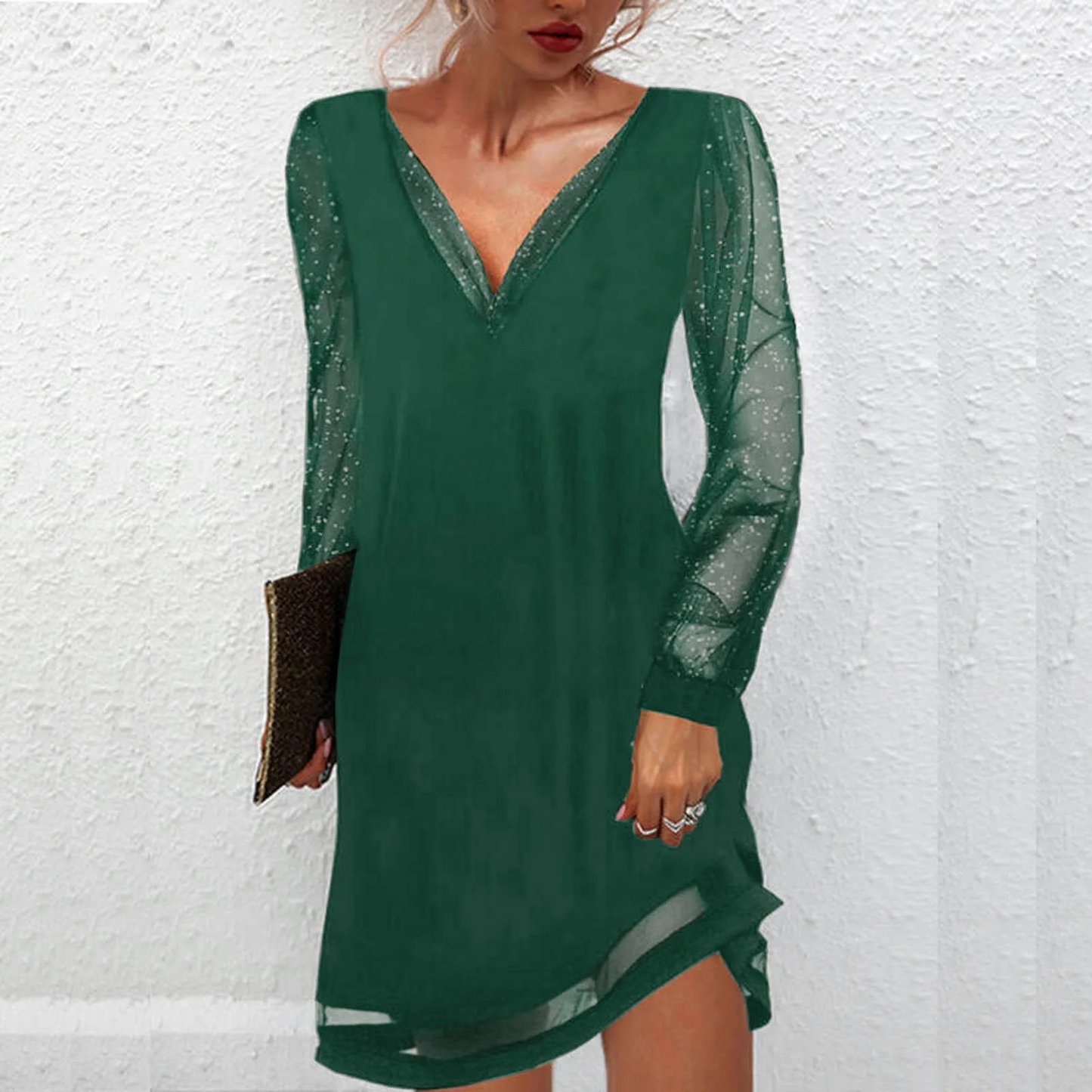 Donna con abito verde elegante, maniche trasparenti scintillanti, tiene una pochette marrone. Moda femminile, abbigliamento da sera chic.