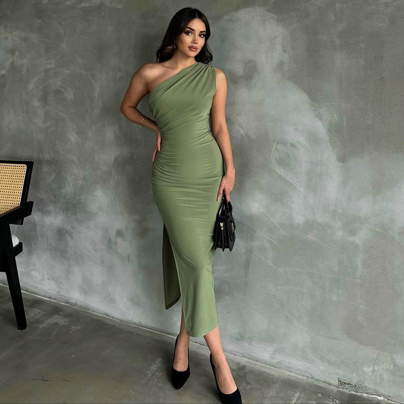 Donna in abito verde elegante, monospalla, posa contro parete grigia. Moda femminile, abbigliamento da sera, stile sofisticato.