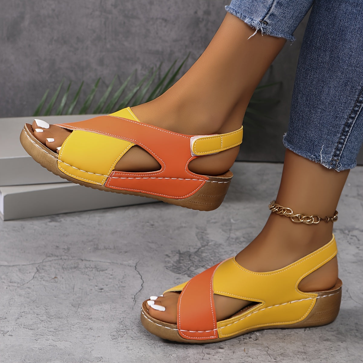 Sandali donna giallo-arancioni con zeppa, design incrociato, indossati con jeans. Scarpe estive eleganti e comode, perfette per look casual.