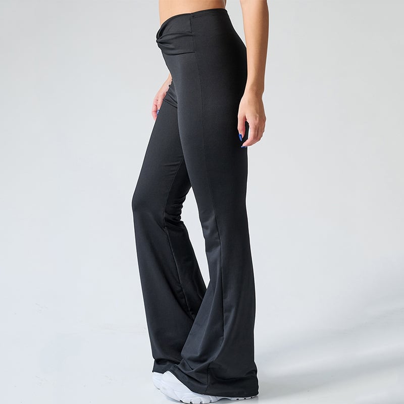 Pantaloni a zampa neri da donna, tessuto elasticizzato, vita alta, stile casual, perfetti per yoga o fitness, abbinati a scarpe sportive bianche.