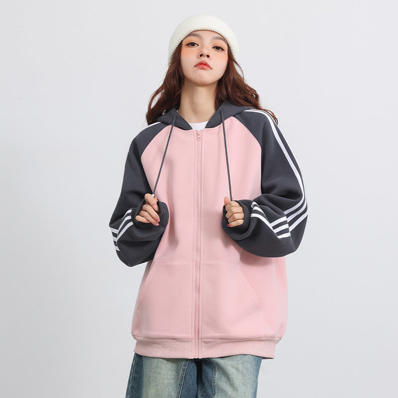 Giovane donna con felpa rosa e cappuccio, maniche a righe bianche, indossa berretto bianco e jeans. Moda casual, abbigliamento streetwear.