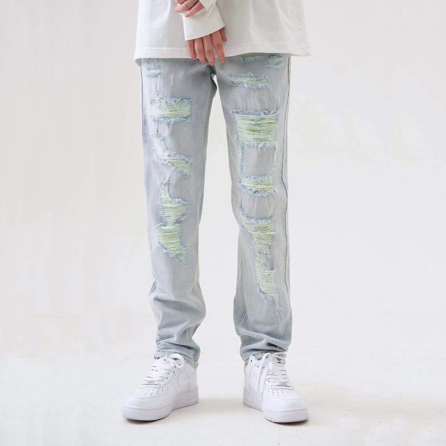 Jeans strappati uomo, colore chiaro, stile casual, abbinati a scarpe da ginnastica bianche. Moda streetwear, tendenze abbigliamento maschile.