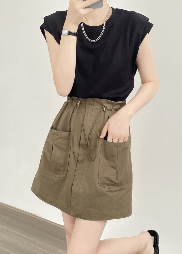 Utente in posa con maglietta nera e gonna verde oliva con tasche grandi, accessori minimalisti. Moda casual femminile, outfit estivo trendy.
