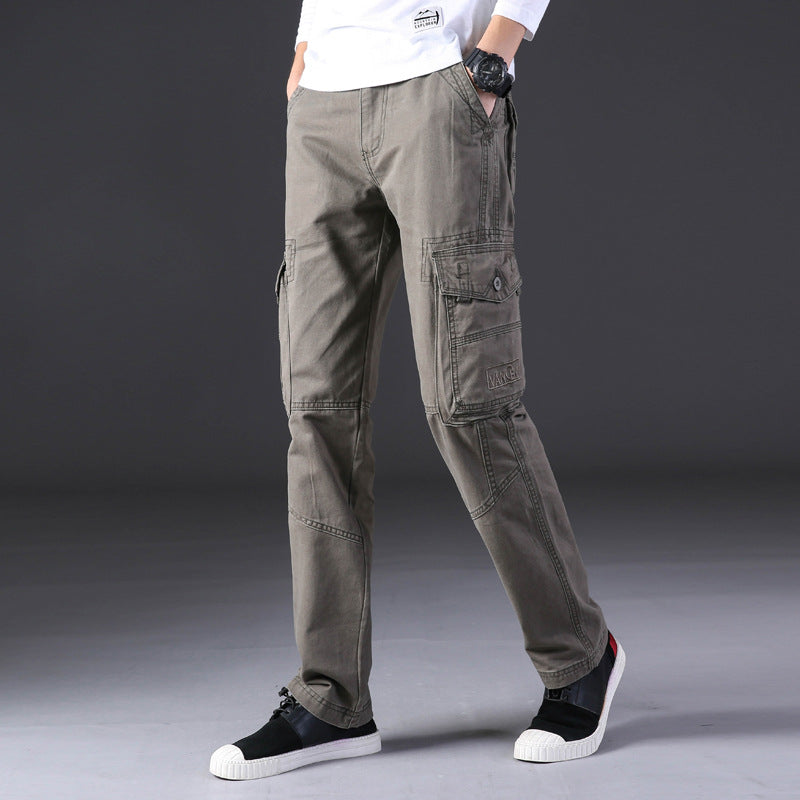 Pantaloni cargo uomo grigi, tasche multiple, stile casual, abbinati a scarpe sportive nere e bianche, sfondo grigio scuro.