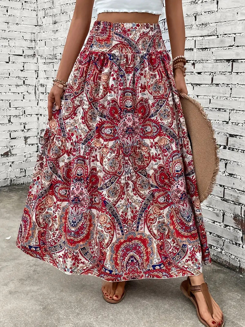 Gonna lunga boho a fantasia floreale rossa e bianca, indossata con sandali marroni. Sfondo di mattoni bianchi. Moda estiva casual.