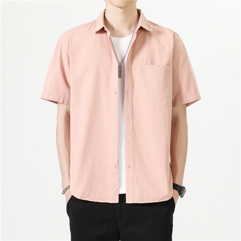 Camicia uomo rosa chiaro a maniche corte, stile casual, con colletto classico e taschino, indossata sopra t-shirt bianca. Moda estiva maschile.