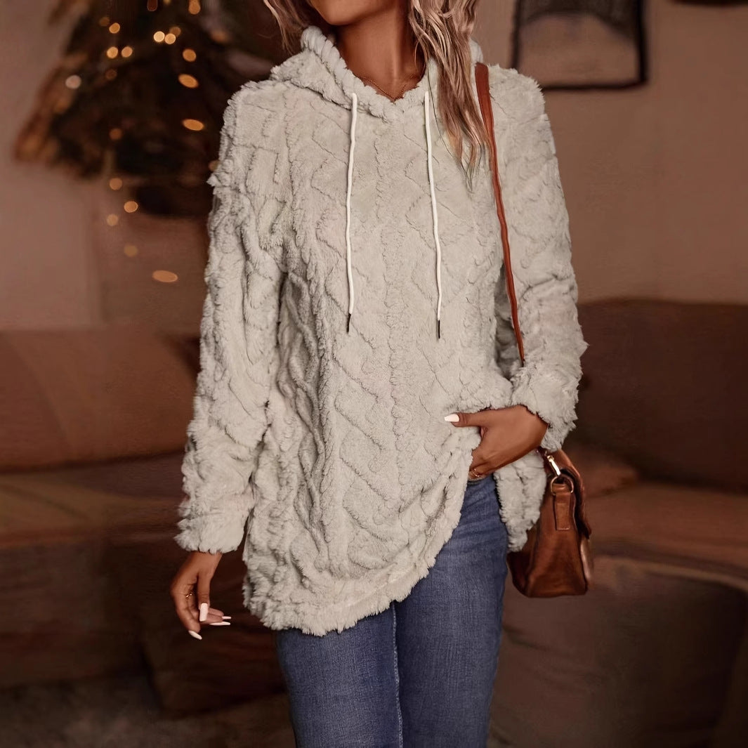 Donna con felpa in pile bianco, cappuccio e jeans, in un ambiente accogliente. Moda autunnale, abbigliamento casual, stile confortevole.
