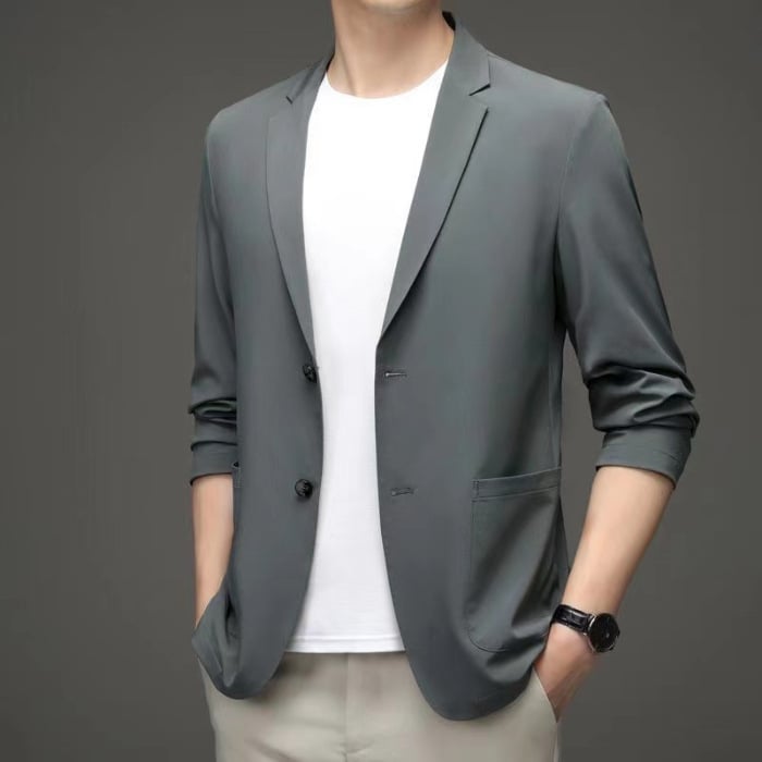 Giacca elegante grigia da uomo su sfondo grigio, abbinata a t-shirt bianca e pantaloni chiari. Moda maschile, abbigliamento casual chic.
