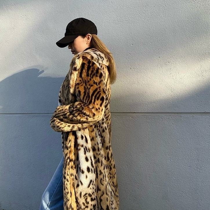 Donna con cappotto leopardato, cappello nero e jeans chiari cammina all'aperto. Moda invernale, stile urbano, tendenze abbigliamento femminile.