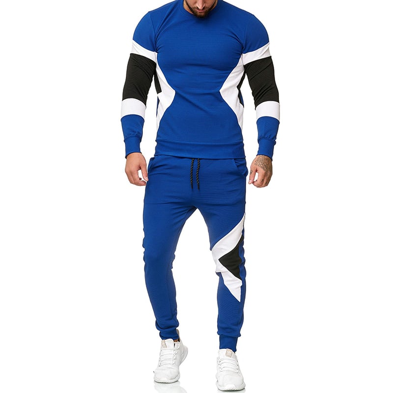 Tuta sportiva uomo blu con dettagli bianchi e neri, maniche lunghe, pantaloni jogger, scarpe da ginnastica bianche. Moda fitness maschile.