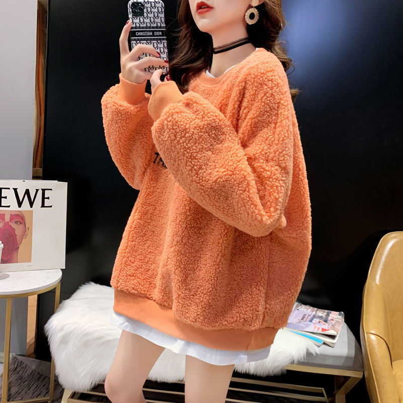 Donna con maglione arancione in pile, specchio, arredamento moderno, moda autunnale, stile casual, accessori eleganti, tendenze abbigliamento 2023.