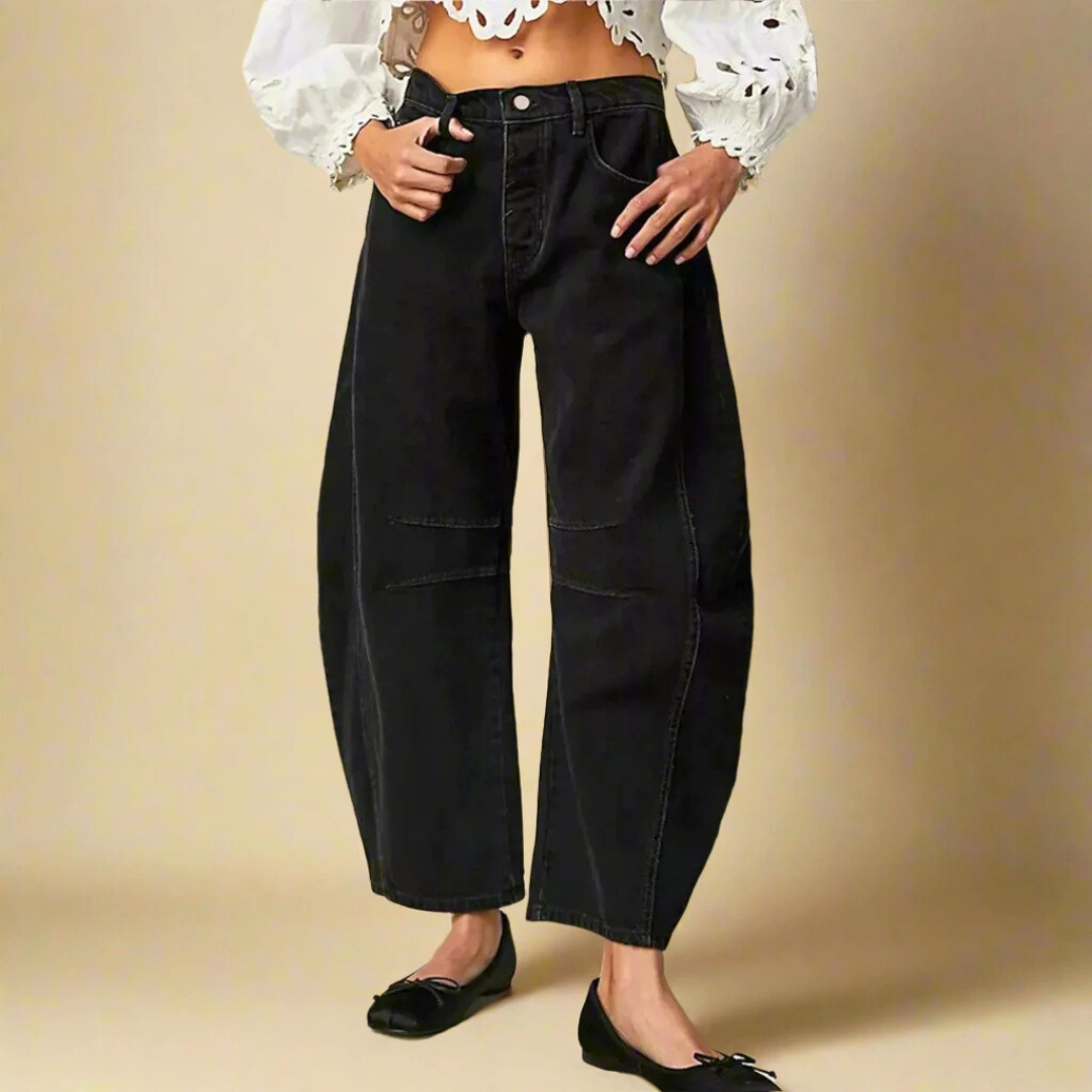 Donna indossa pantaloni neri larghi a vita alta, abbinati a una camicetta bianca con maniche a sbuffo. Moda casual femminile elegante.
