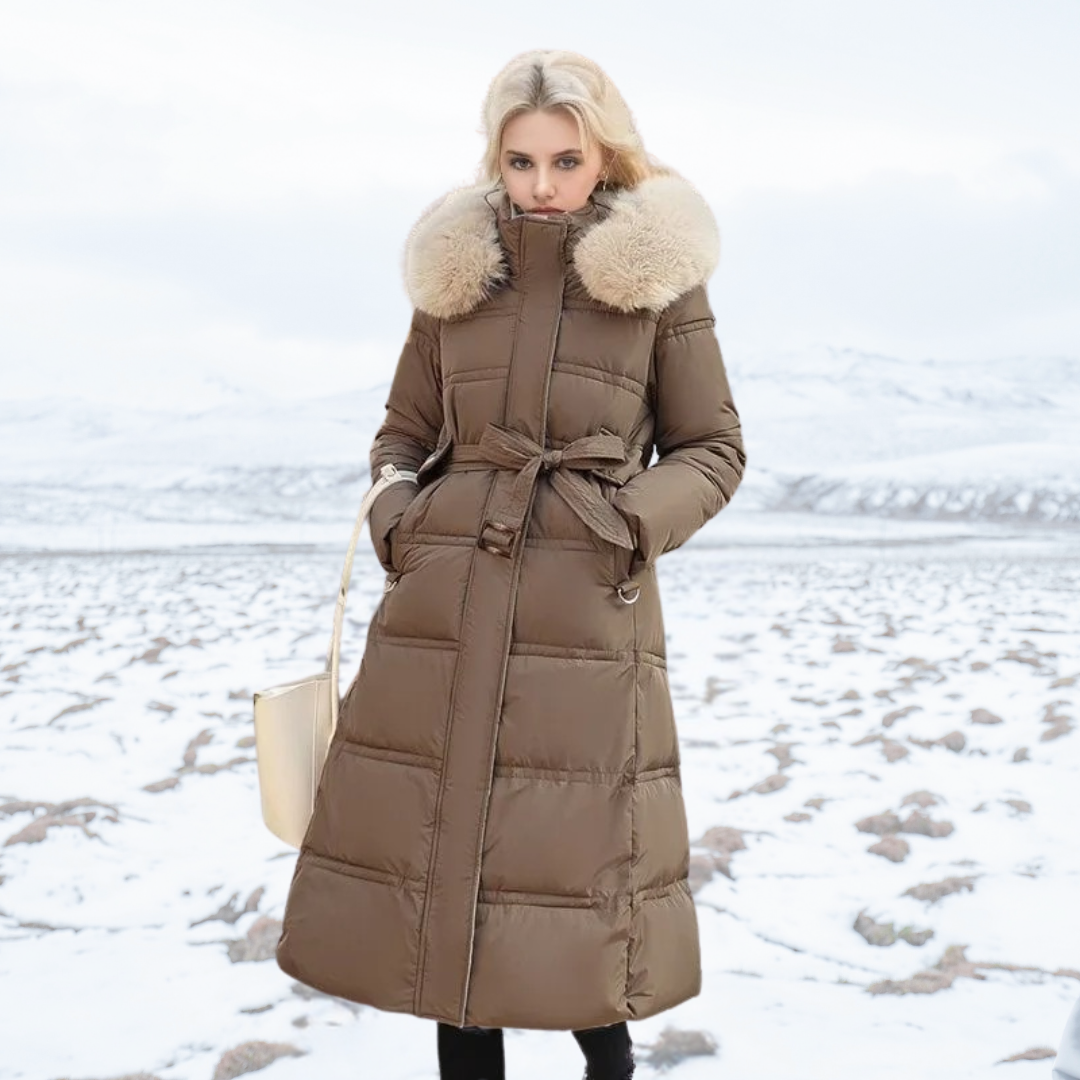 Donna con cappotto invernale marrone con cappuccio in pelliccia, in piedi su paesaggio innevato. Moda inverno, abbigliamento caldo, stile elegante.