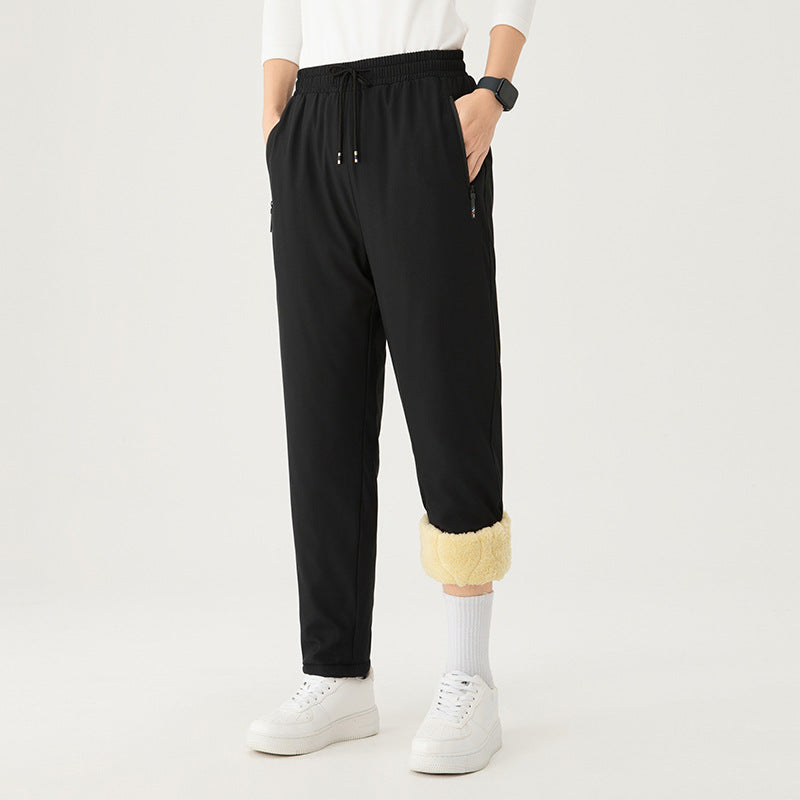 Pantaloni neri invernali con fodera in pile, elastico in vita, tasche laterali, indossati con scarpe bianche. Abbigliamento casual caldo.