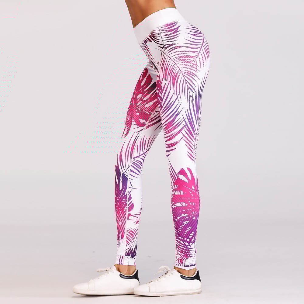 Pantaloni leggings sportivi donna con stampa foglie tropicali rosa e viola, abbinati a scarpe da ginnastica bianche. Fitness, moda activewear.