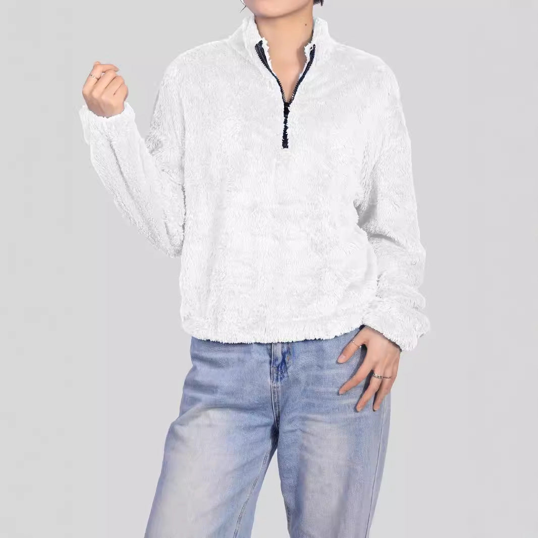 Donna con maglione bianco in pile, zip frontale, indossa jeans chiari. Moda casual autunnale, abbigliamento comodo e caldo. Sfondo grigio.