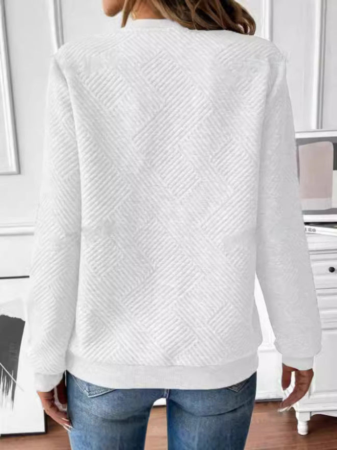 Donna con maglione bianco a trama geometrica, vista posteriore, in una stanza moderna. Indossa jeans blu. Moda casual autunnale.