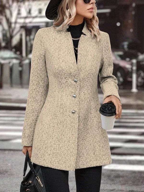 Donna con cappotto beige elegante, cappello nero e occhiali da sole, tiene una tazza di caffè e una borsa nera, sfondo urbano sfocato.