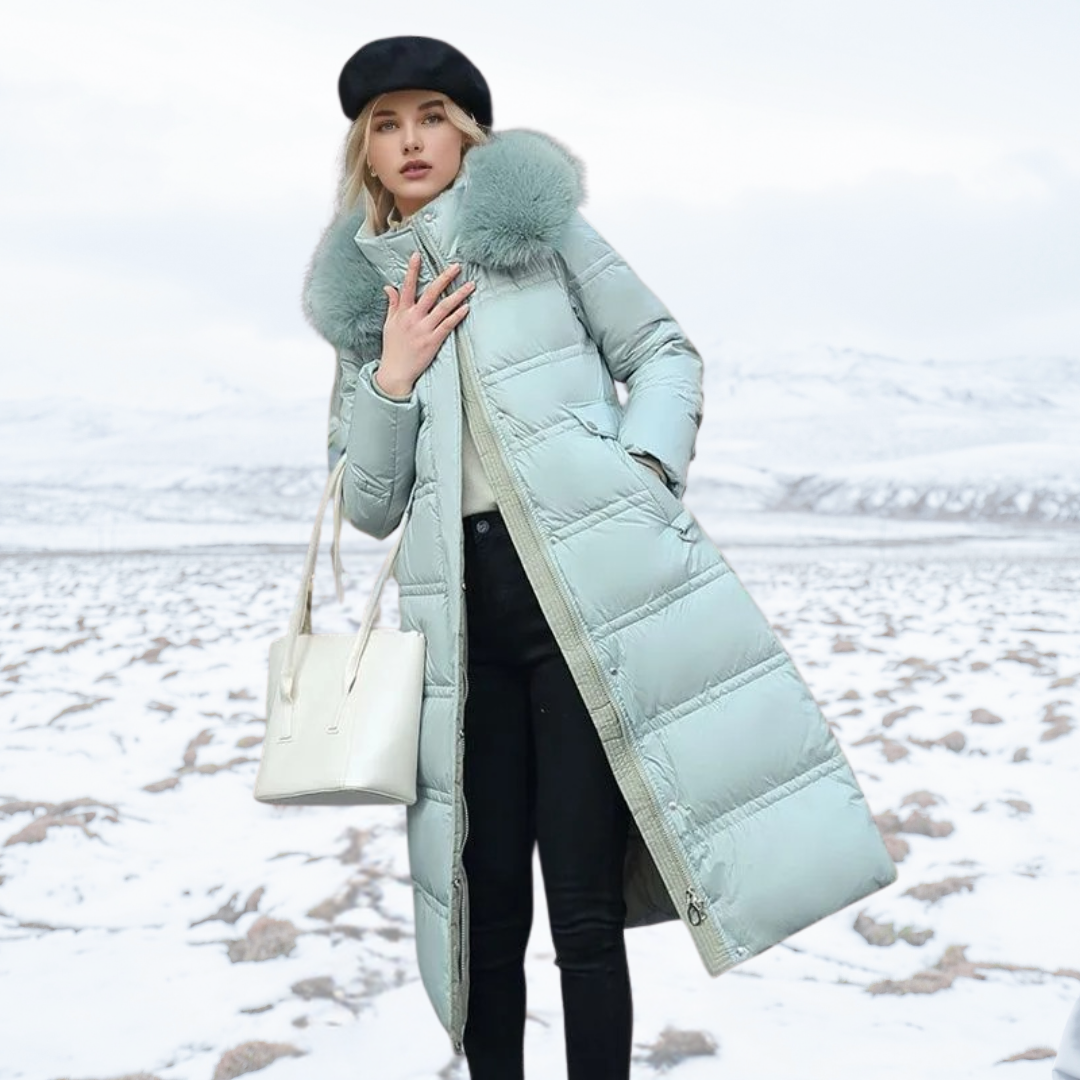 Donna con cappotto lungo verde menta invernale, berretto nero e borsa bianca, in paesaggio innevato. Moda invernale, abbigliamento caldo.