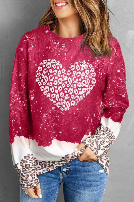 Donna con maglione rosso a cuore leopardato, maniche con dettagli animalier, jeans casual. Moda autunno, stile casual chic, tendenze abbigliamento.