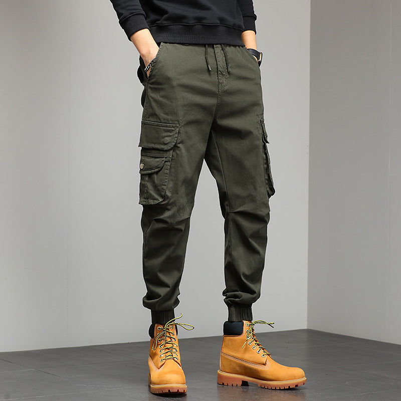 Pantaloni cargo verde militare da uomo con tasche multiple, abbinati a stivali gialli. Stile casual e funzionale per moda urbana.